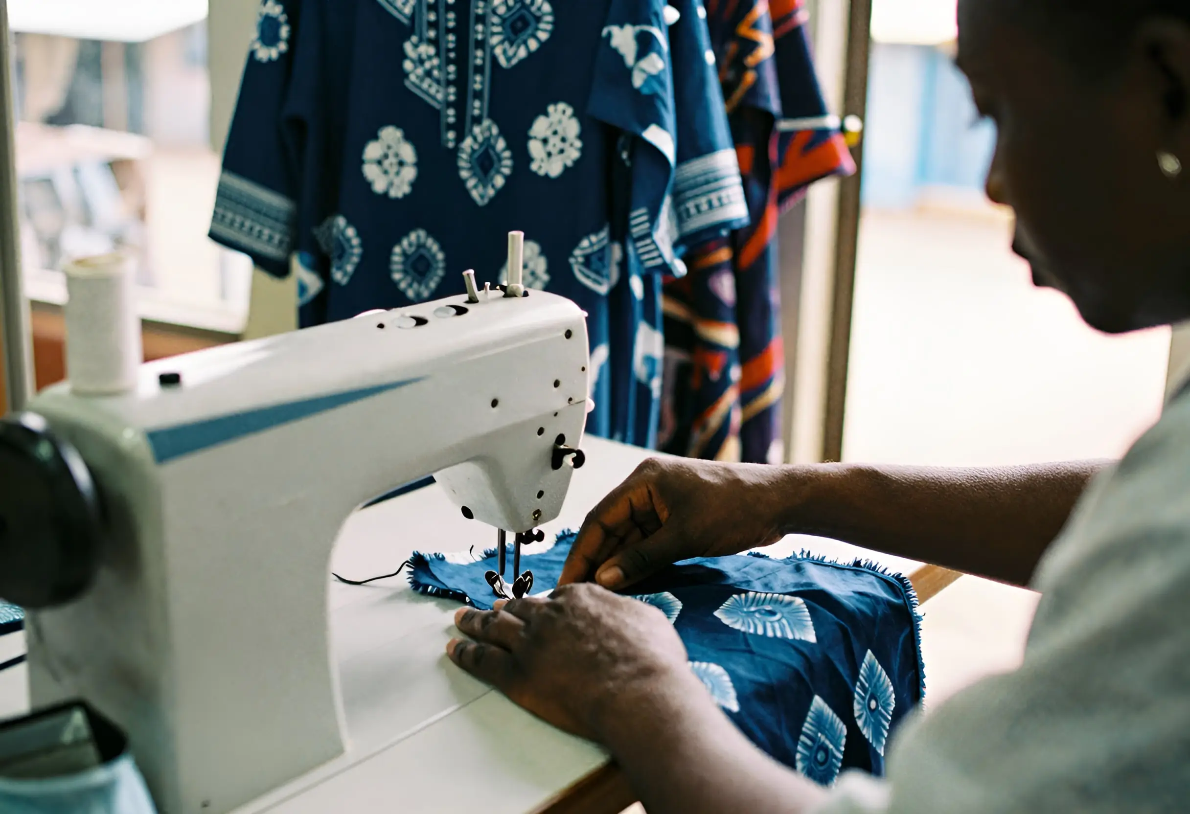 A tailor guiding patterned fabric through a sewing machine